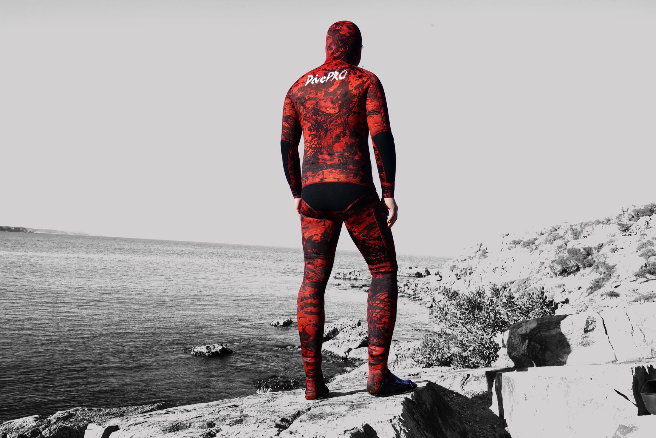 DivePRO diver in a red wetsuit looking over the coast